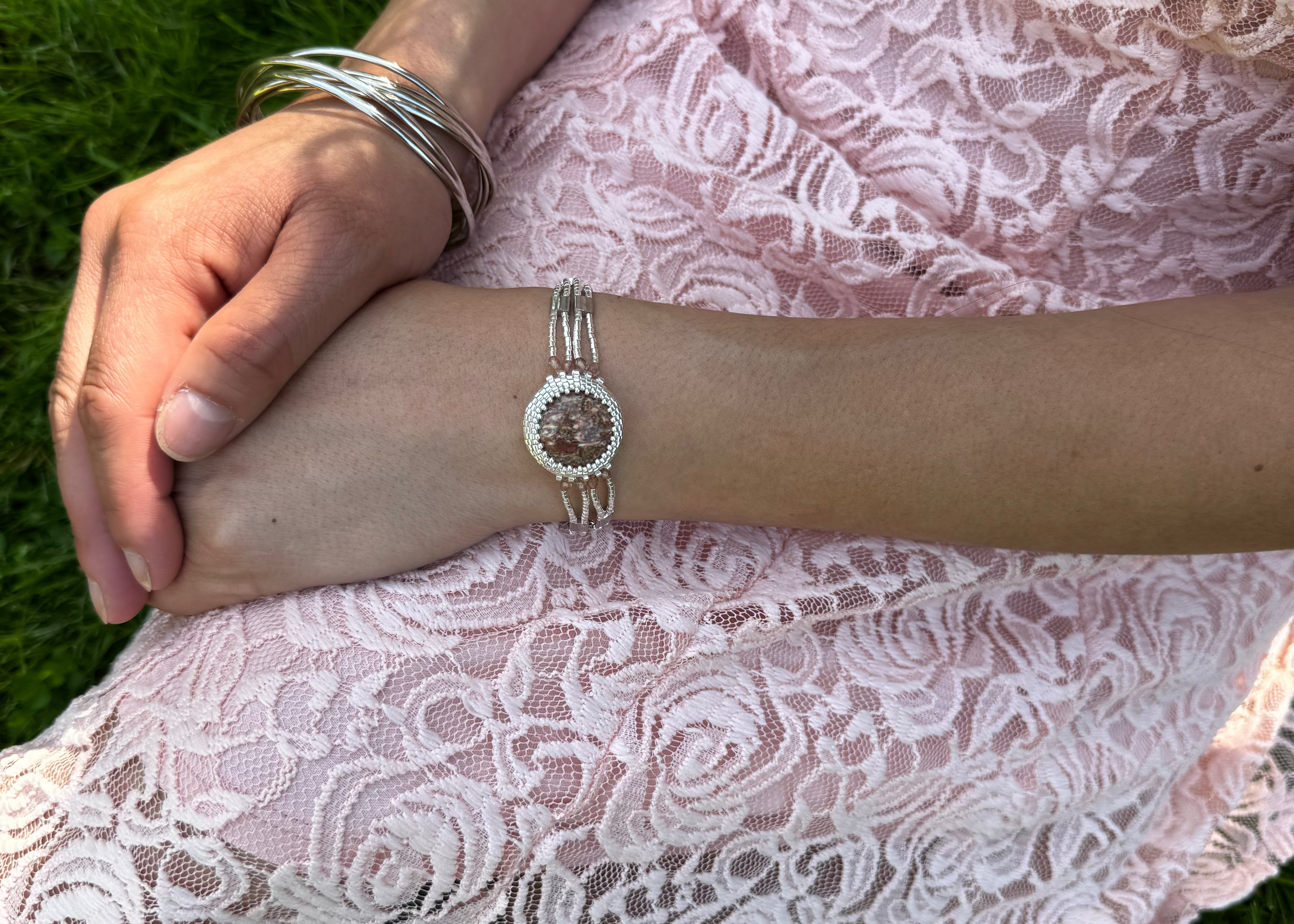 Person wearing a pink lace dress and silver bracelet with a leopard jasper stone for inner strength, emotional balance, and spiritual connection to your spirit animal in crystal healing.